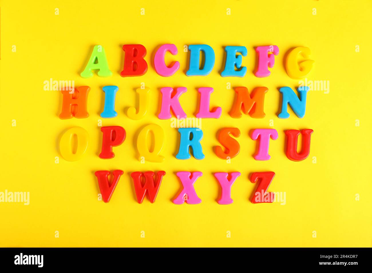 Lettere magnetiche in plastica su sfondo giallo, a giacitura piatta. Ordine alfabetico Foto Stock