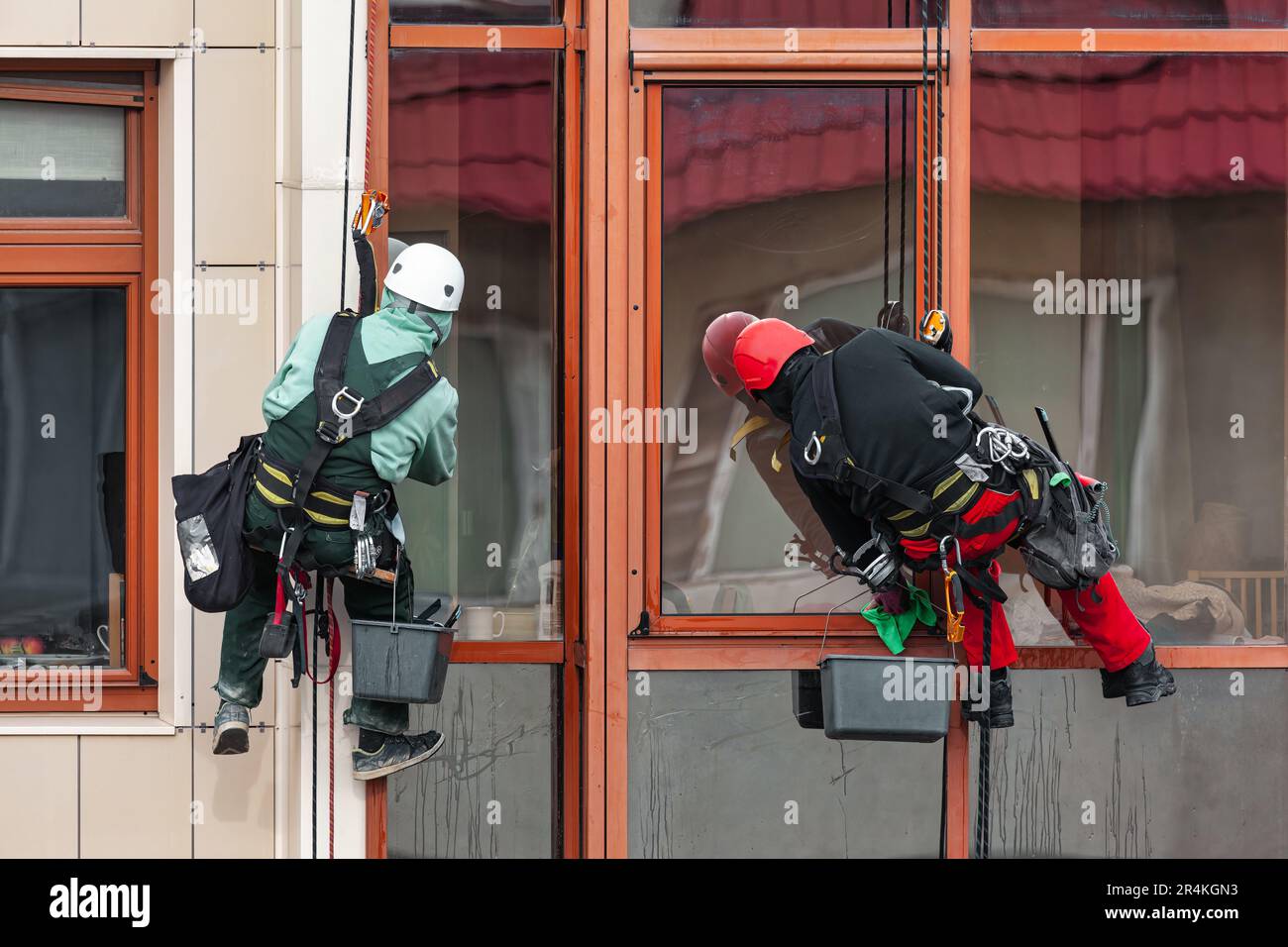 Lavoratori lavano le finestre all'esterno dell'edificio. Servizi di pulizia finestre con accesso a funi Foto Stock