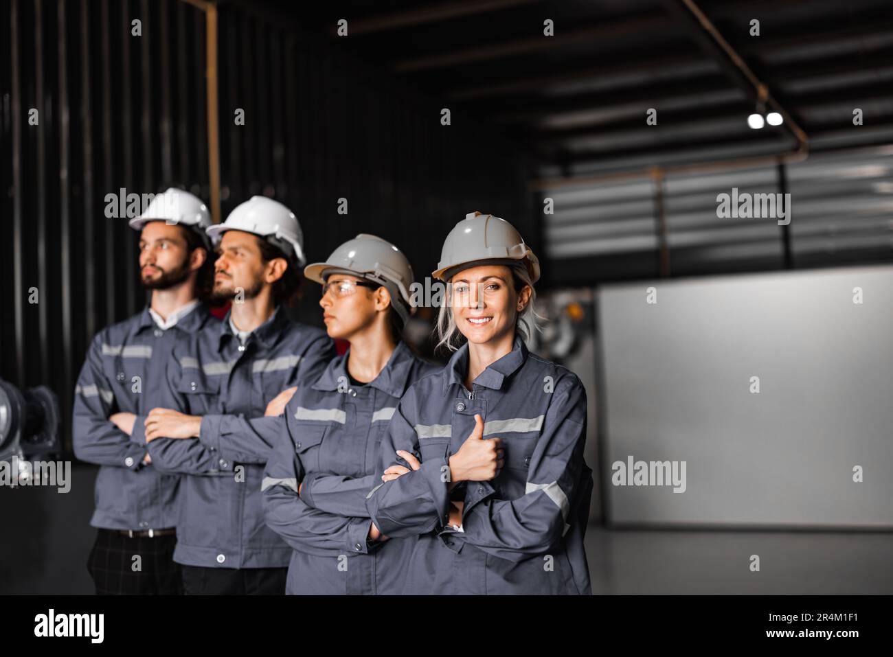 Un team robotico sicuro, tra cui donne che vivono in campi non tipicamente maschili, attraversa le braccia per rappresentare l'impegno dell'azienda verso la diversità e l'inclusione Foto Stock