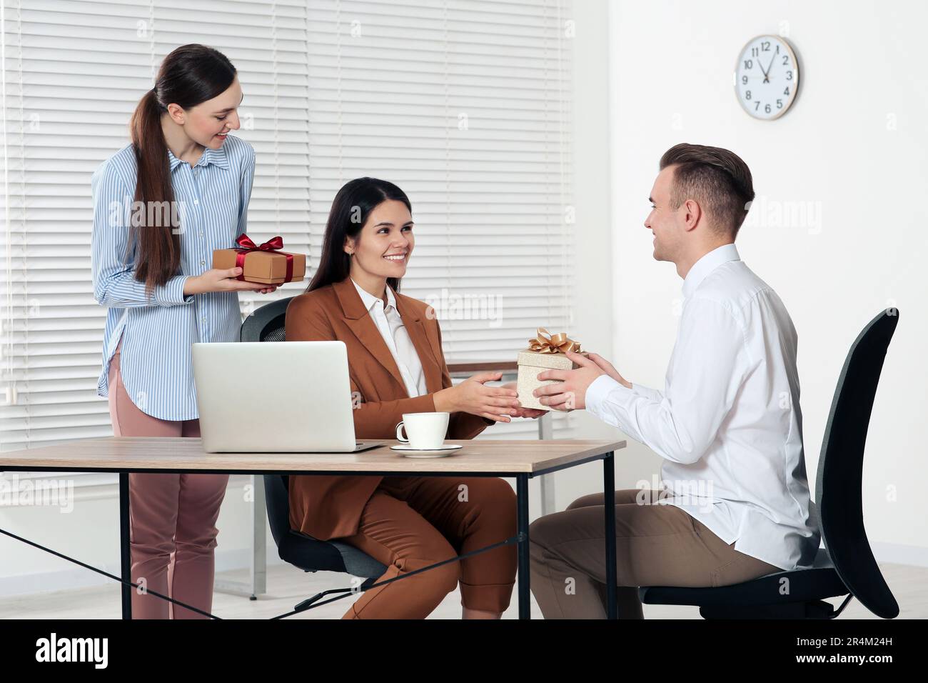 Donna che presenta un regalo alla sua collega in ufficio Foto stock - Alamy