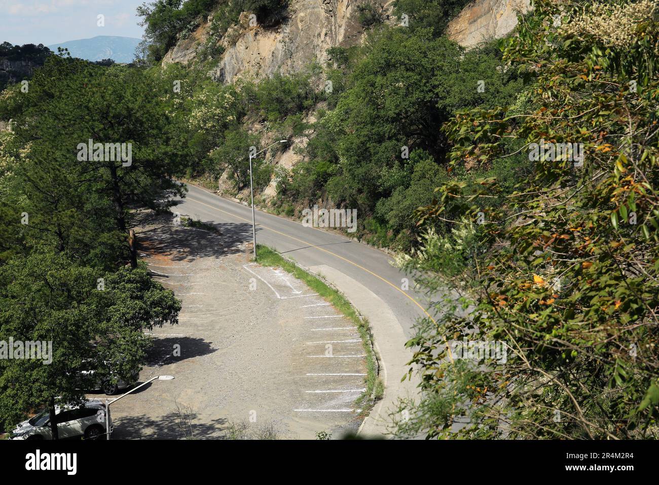 Strada e parcheggi con marcature dipinte su asfalto vicino montagne all'aperto Foto Stock