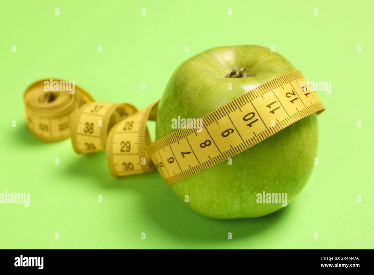 Concetto di perdita del peso. Apple e metro a nastro su sfondo verde, primo piano con spazio per il testo Foto Stock