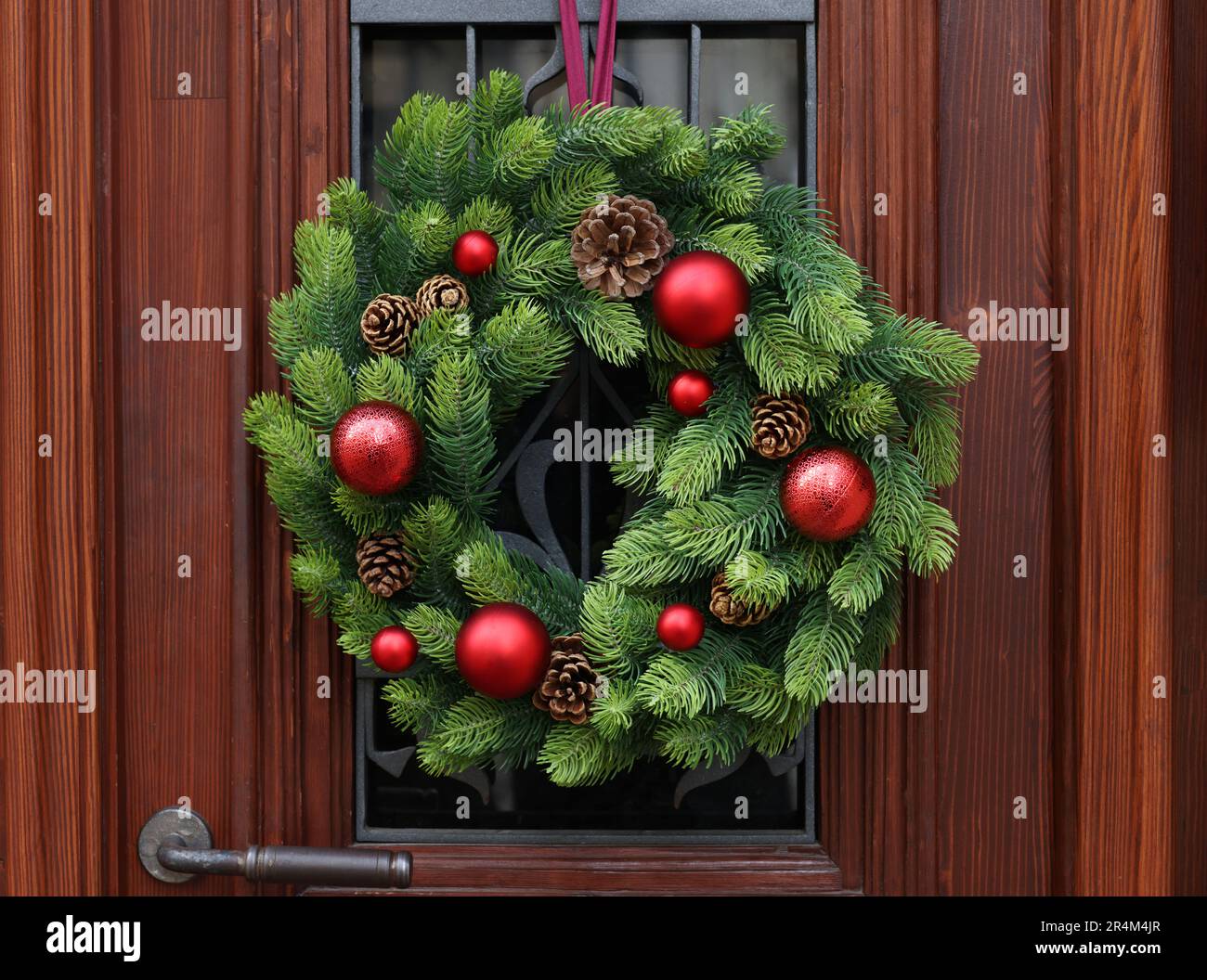 Bella corona di Natale appesa su una porta di legno Foto Stock