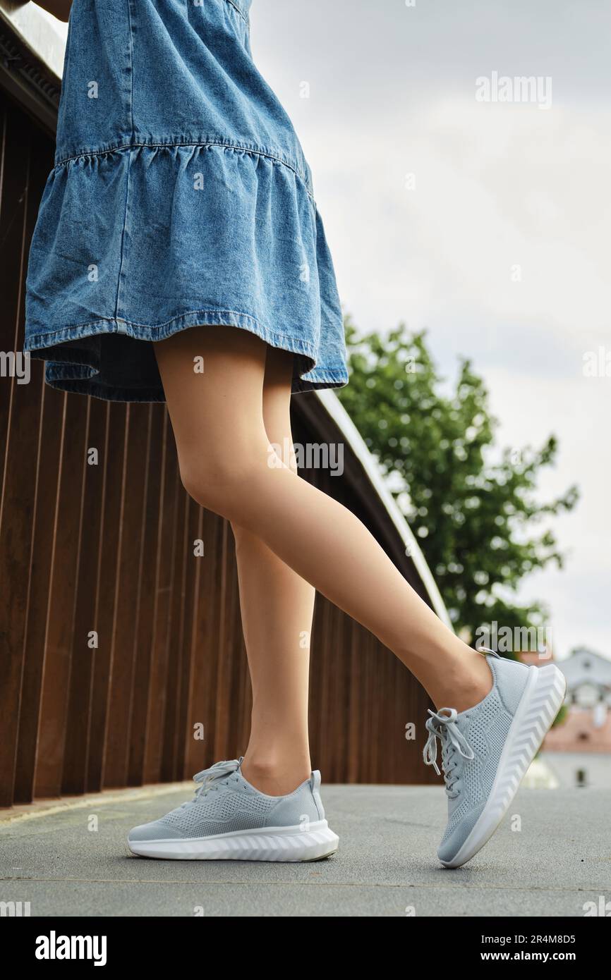 Gambe di donna irriconoscibile in tights e sneakers beige Foto Stock