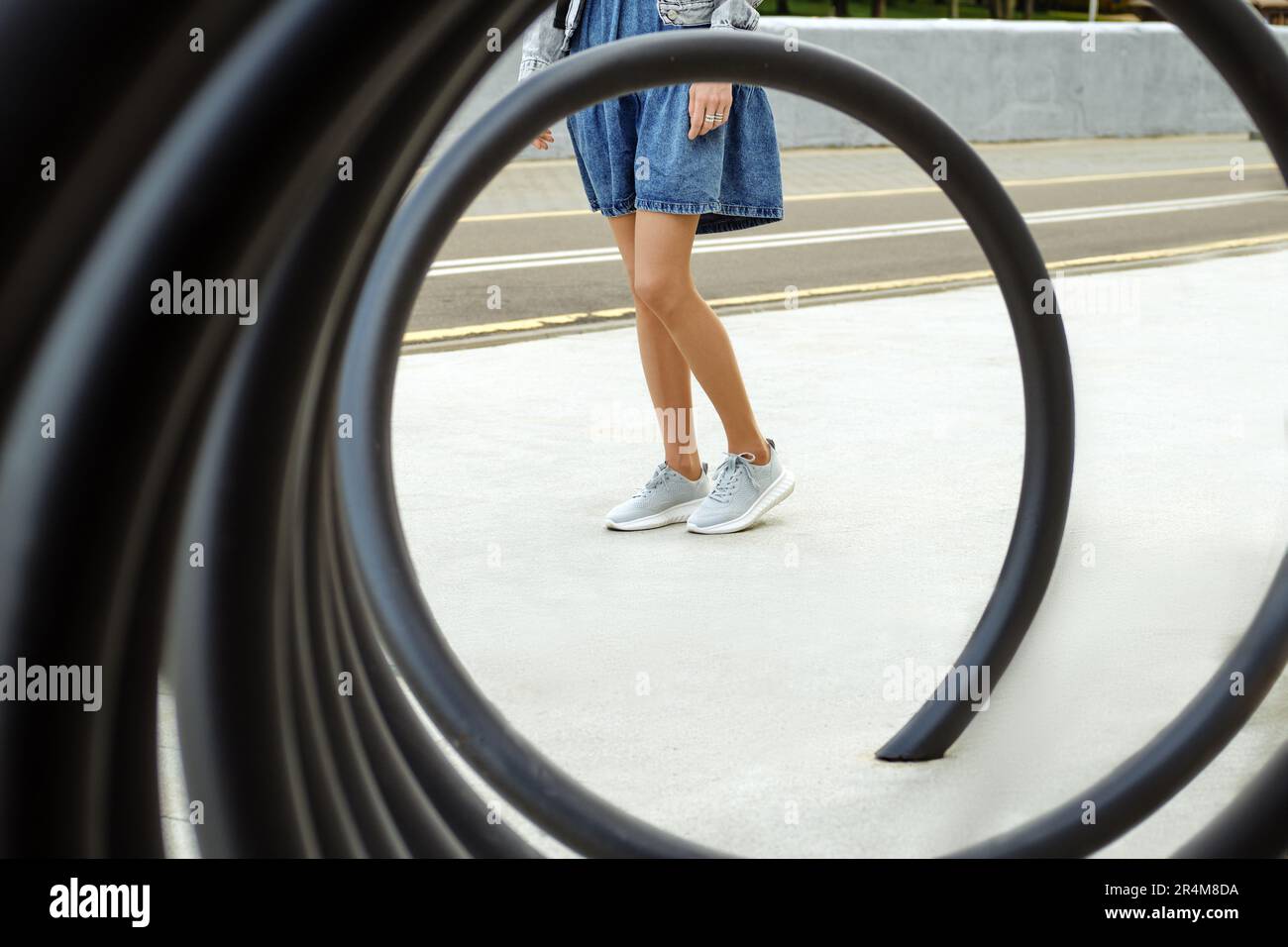 Ammira la spirale metallica sulle gambe di una donna irriconoscibile in collant e sneaker beige Foto Stock