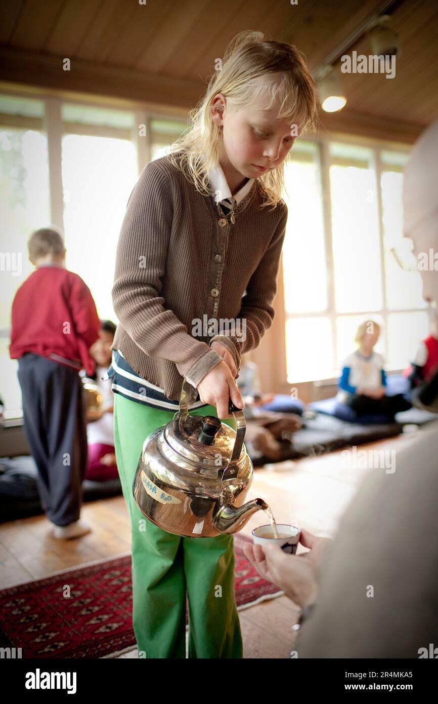 Una ragazza giovane serve il tè ad un alter durante un ritiro di famiglia buddista sull'Isola di Vashon, Washington. Foto Stock