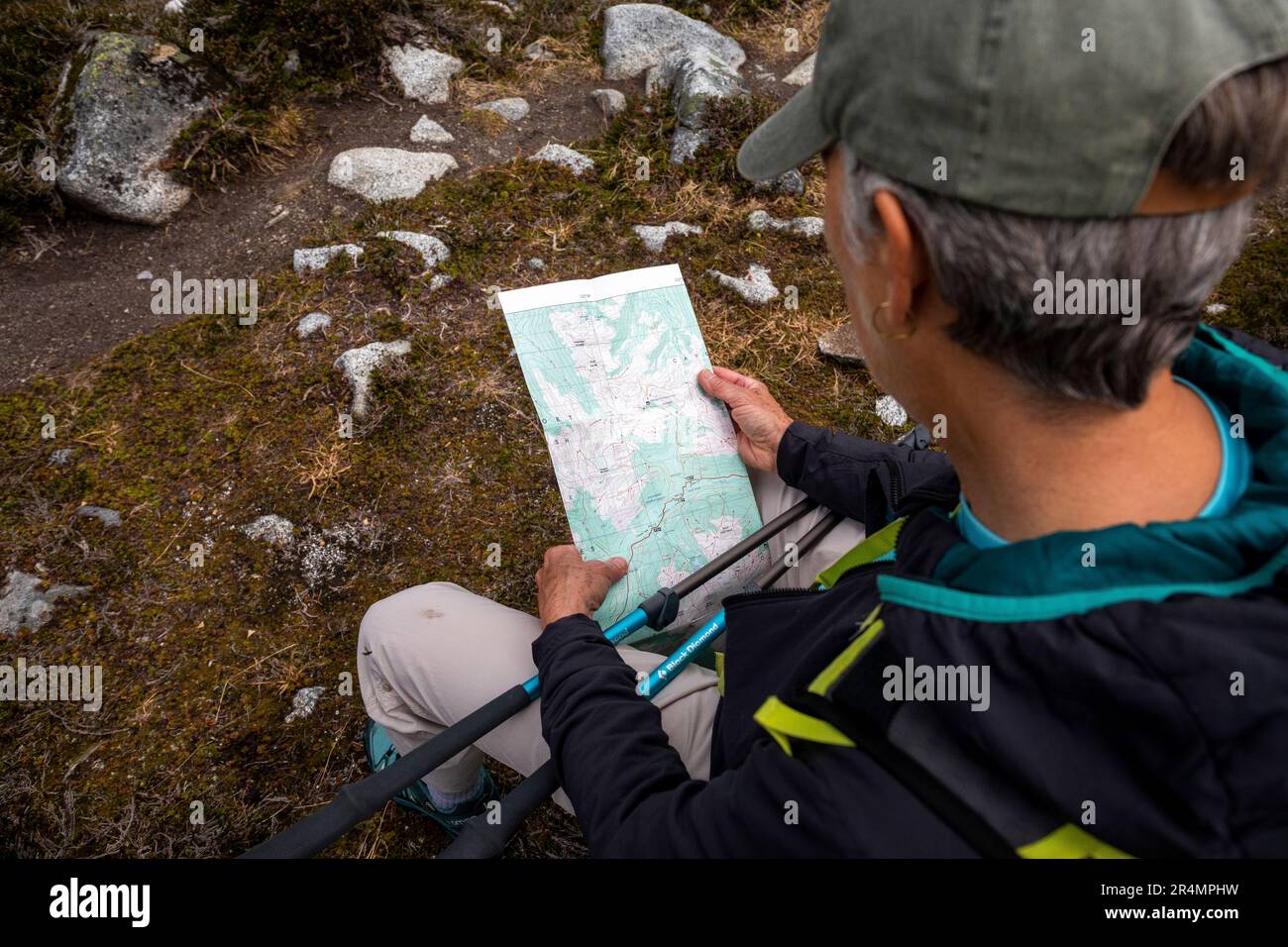 Vista laterale di una donna con zaino che guarda una mappa durante le escursioni. Foto Stock