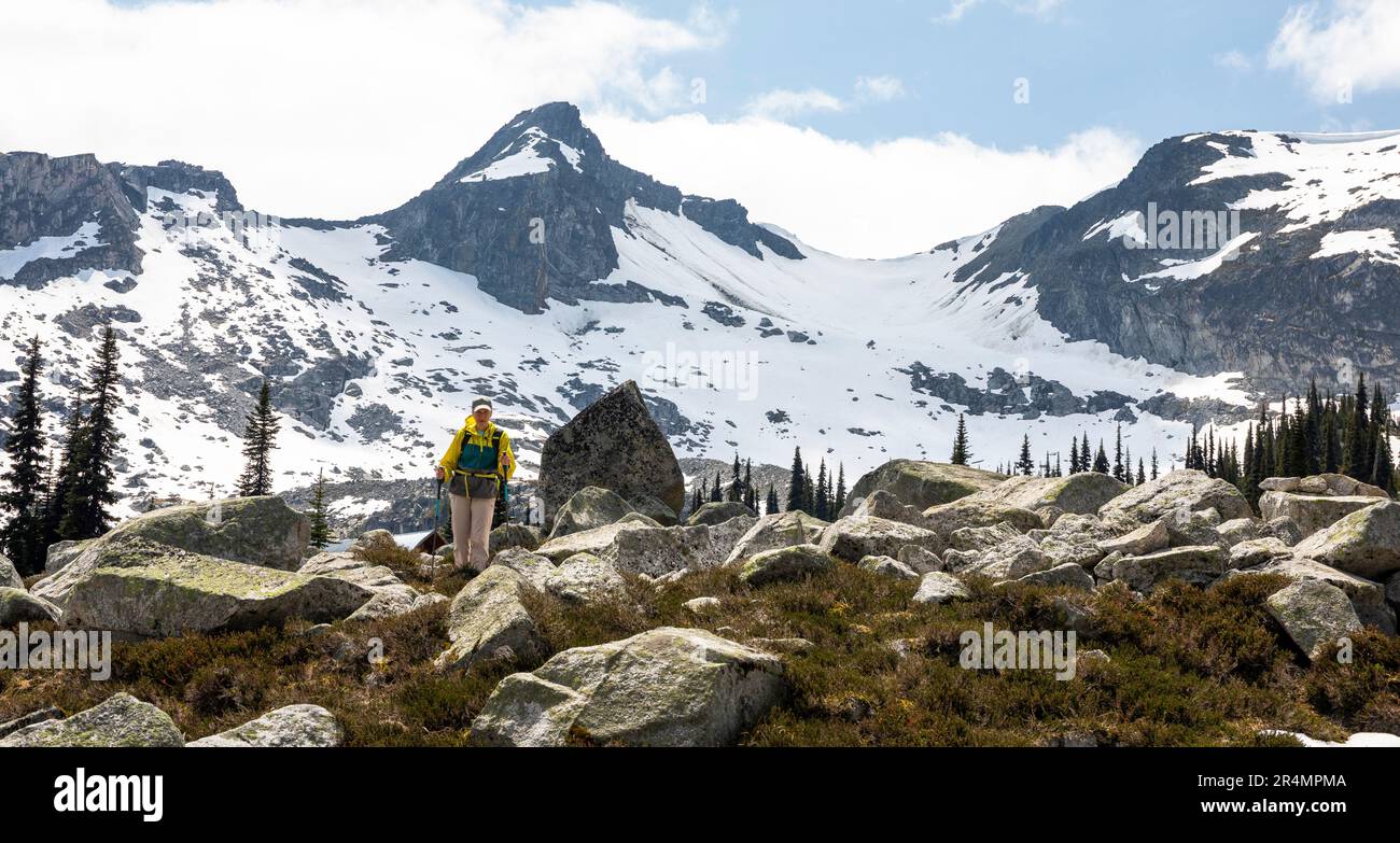 Vista ad angolo basso delle donne che camminano sulle montagne sostenute da neve e roccia. Foto Stock