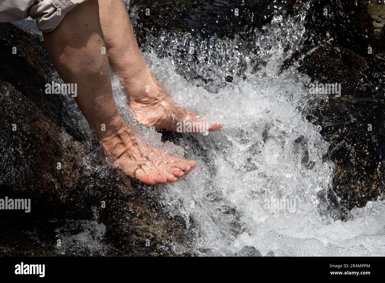 Vista dettagliata delle donne che raffreddano i piedi stanchi in un freddo fiume alpino Foto Stock
