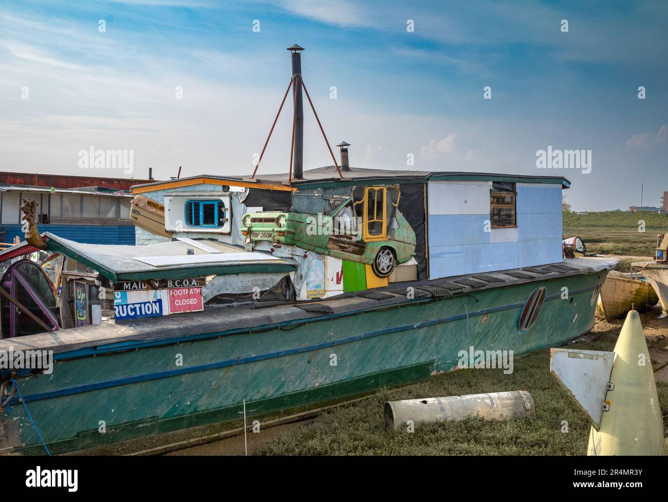 Un eccentrico houseboat ormeggiato a Shoreham by Sea, West Sussex, Regno Unito. La casa galleggiante è fatta da una vecchia chiatta, un'automobile Reliant Robin a tre ruote ed othe Foto Stock