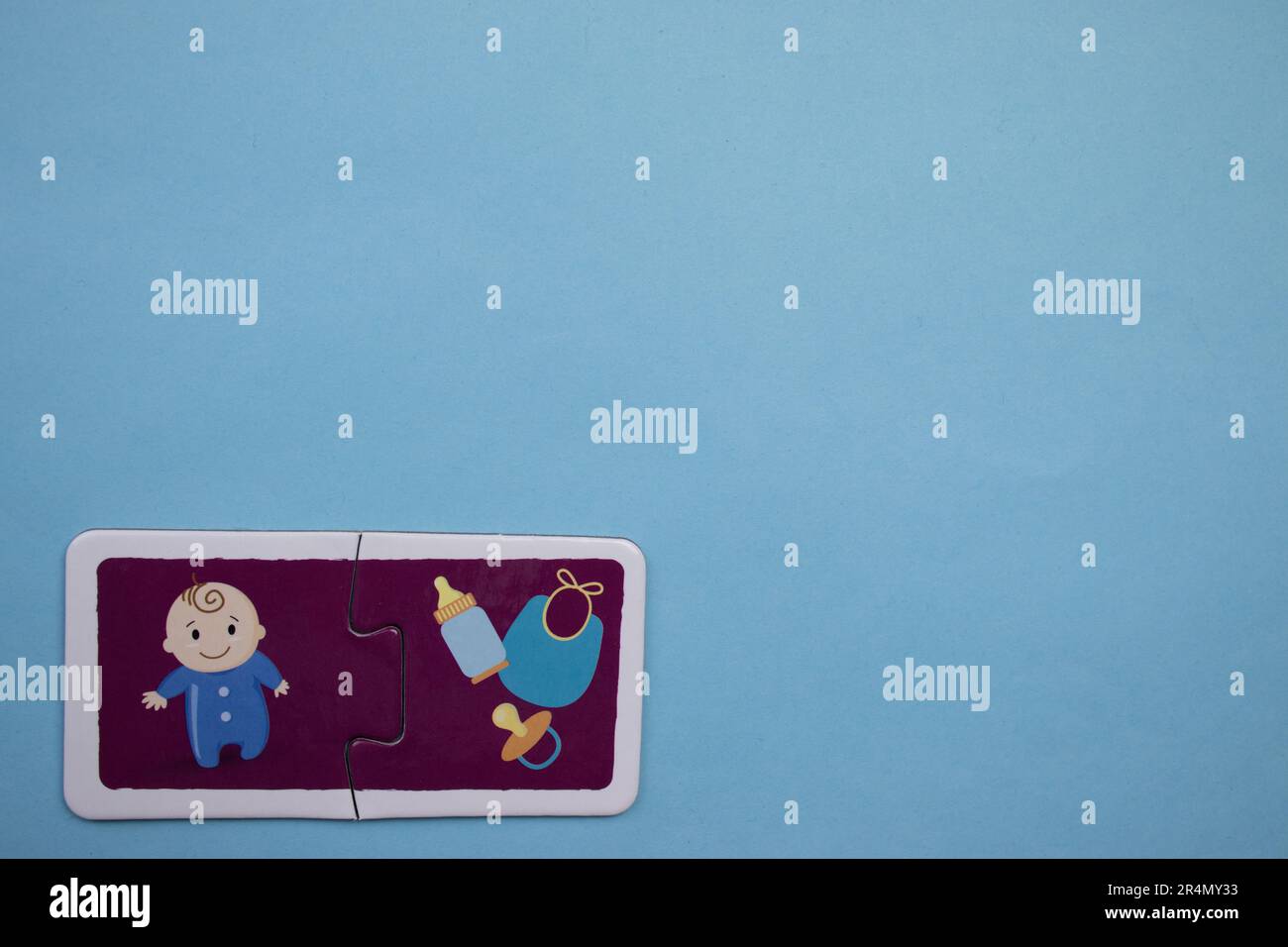 Puzzle di immagine posti sul bordo di uno sfondo blu. Bambino e bambino paraphernalia. Foto Stock