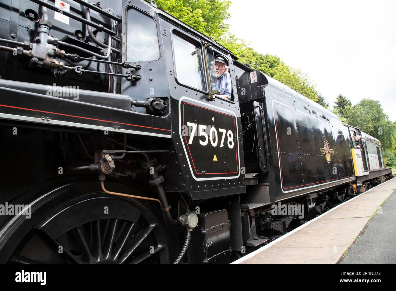 Una vista a livello della piattaforma della locomotiva a vapore 75078 BR Standard Class 4mt 4-6-0 che arriva alla stazione di Oxenhope sulla ferrovia di Keighley & Worth Valley Foto Stock