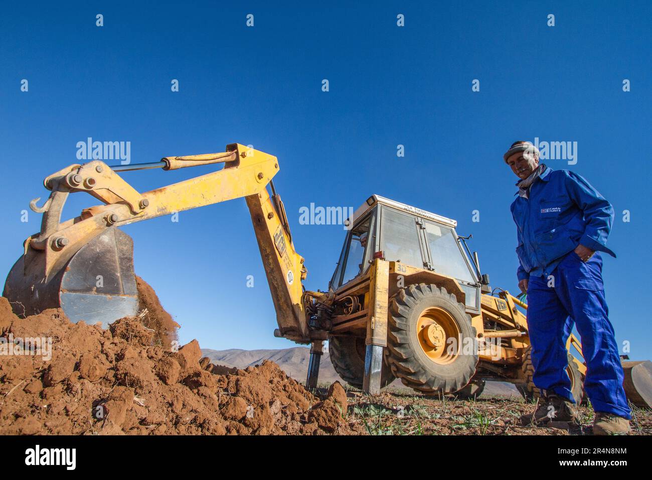 Coltivatore che utilizza un retroescavatore per preparare il suo campo per la piantagione di Almond Tree Foto Stock