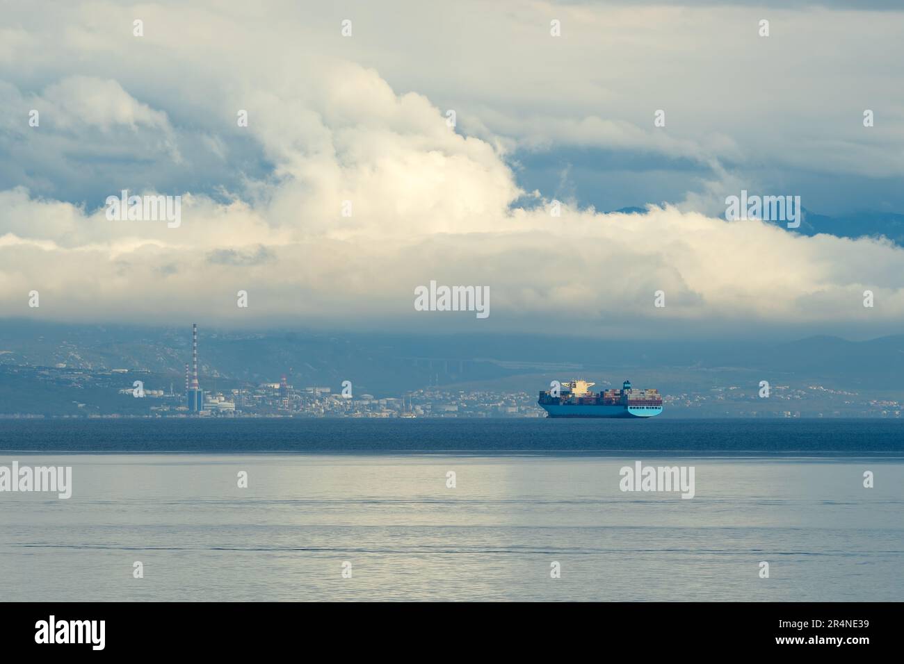 Grande nave container che naviga in mare in mattinata sovrastata vicino al litorale della città di Rijeka in Croazia, focus selettivo Foto Stock