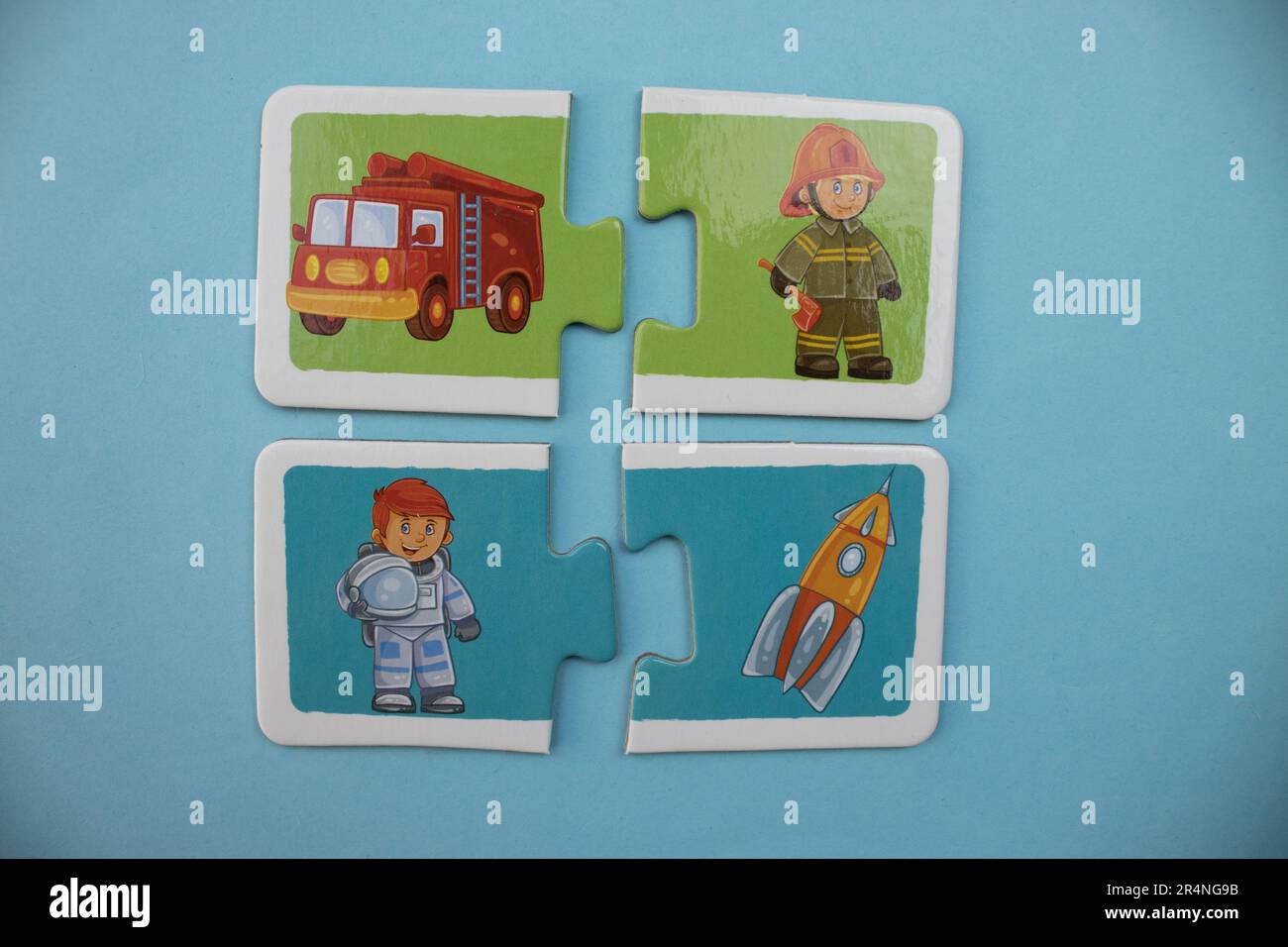 Puzzle di immagine disposti su uno sfondo blu. Astronauta, astronave, vigili del fuoco e camion dei pompieri. Foto Stock
