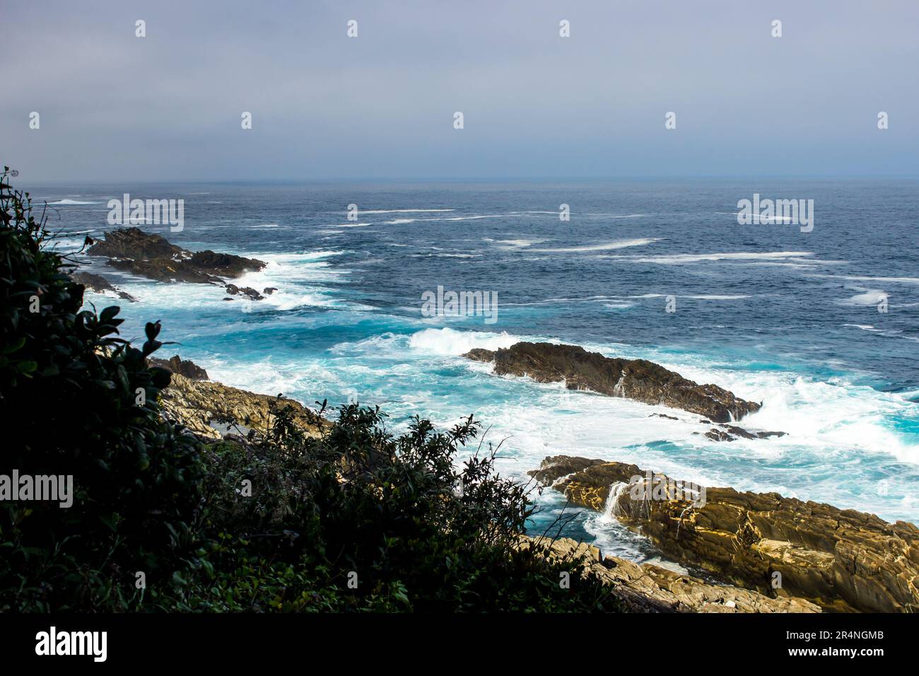 Affacciato sui mari temibili della costa di Tsitsicamma, Sudafrica, con scogliere rocciose parzialmente sommerse. Foto Stock