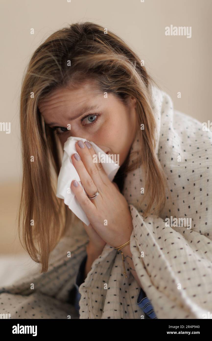 Ritratto di giovane donna malata starnutendo in camera da letto. Foto Stock