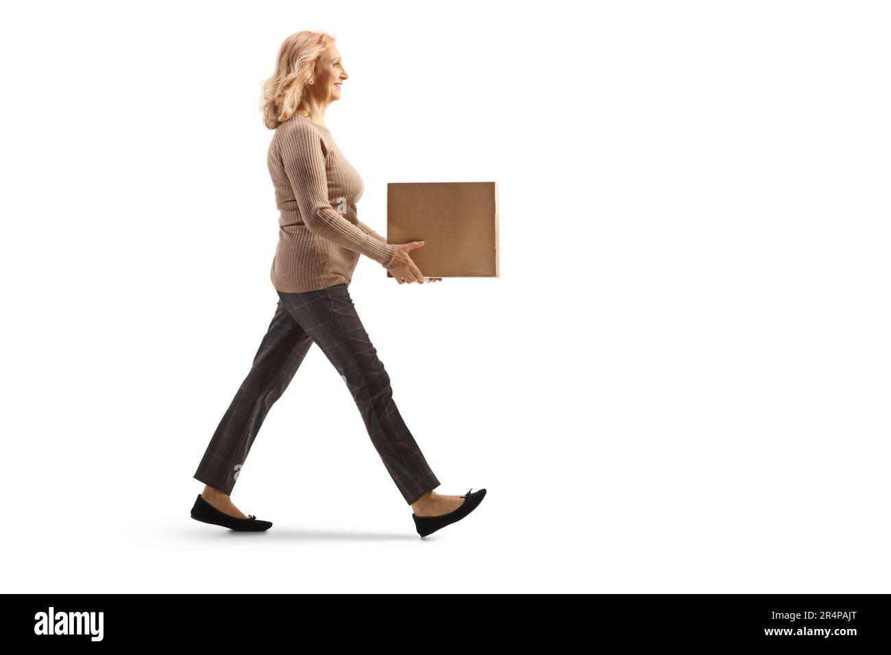 Profilo a tutta lunghezza di una donna matura che cammina e porta una scatola isolata su sfondo bianco Foto Stock