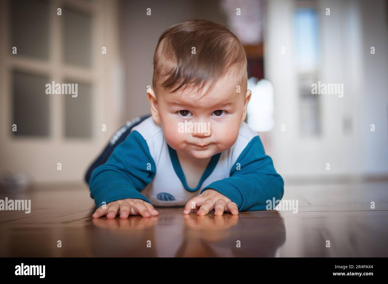 Cute baby boy striscia sul pavimento di casa, esplorare il mondo e imparare a muoversi. Amore ed emozione familiare Foto Stock