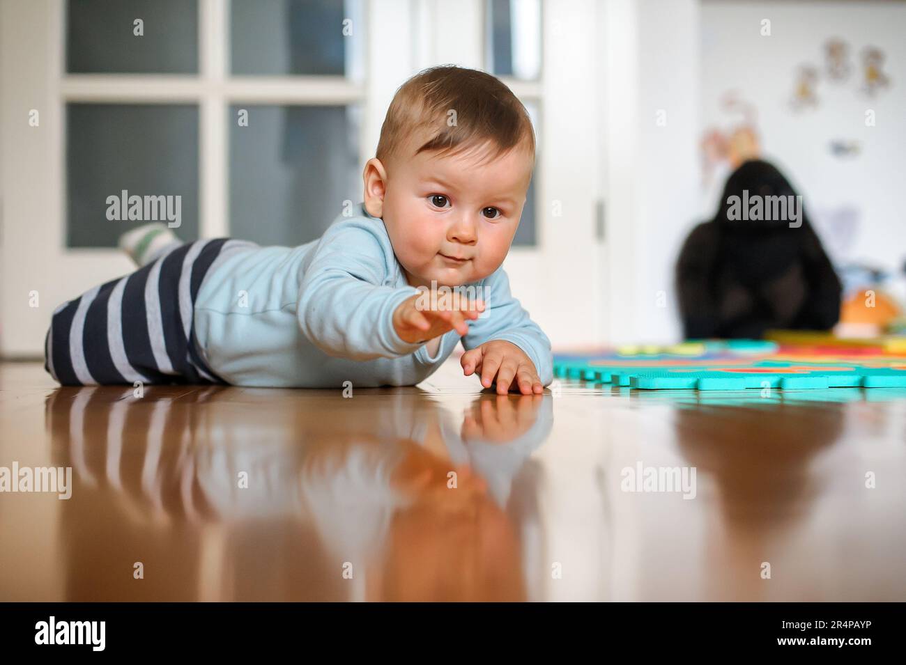 Cute baby boy striscia sul pavimento di casa, esplorare il mondo e imparare a muoversi. Amore ed emozione familiare Foto Stock