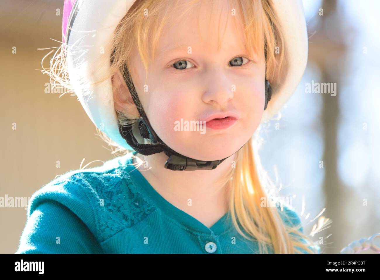 Ritratto di una ragazza caucasica bionda di quattro anni che indossa un casco da bicicletta e guarda la macchina fotografica. Foto Stock