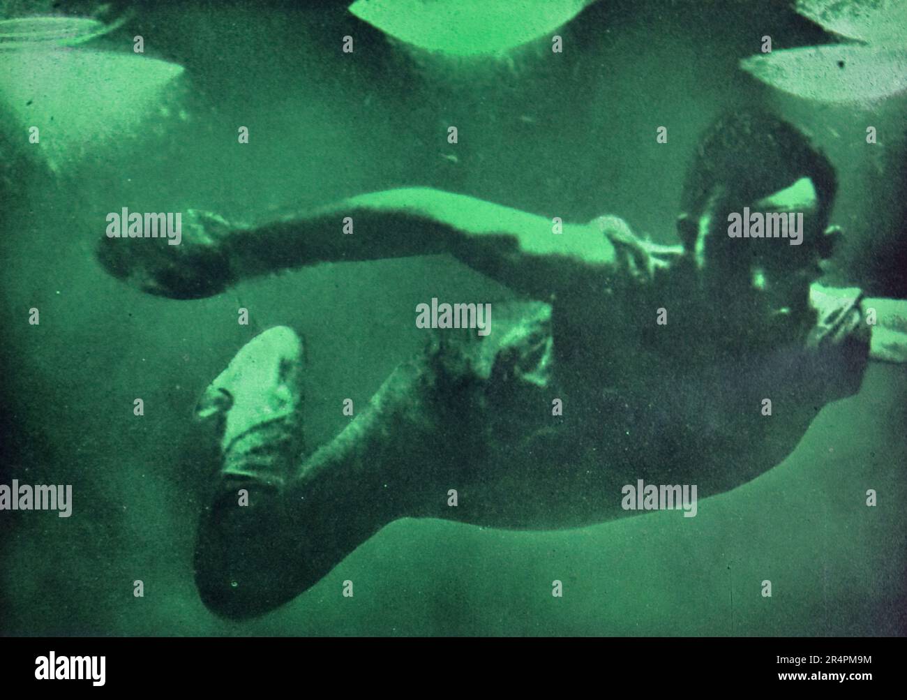 La spedizione sottomarina di Williamson del 1914 è stata la prima a rivelare alcuni dei tesori sotto la superficie dell'oceano. Grazie in gran parte a tecniche fotografiche innovative la biologia marina intorno alle Bahamas è entrata in vita. Questa foto mostra: Fotografia di mezzanotte: Subacqueo nativo che nuota sotto le potenti lampade al vapore di mercurio. Foto Stock
