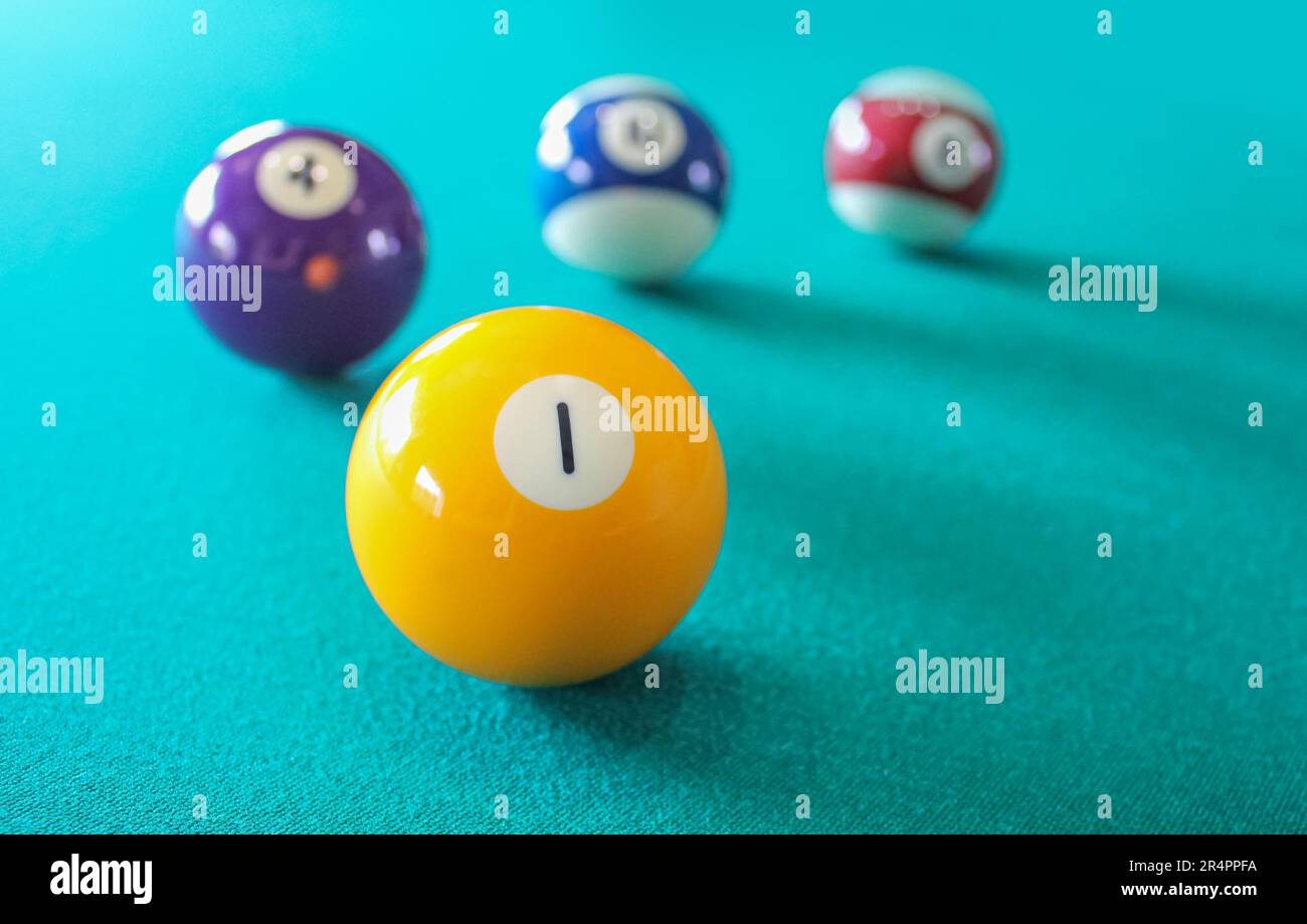 Un biliardo giallo numero 1 su una superficie verde tavolo da biliardo con sfondo sfocato di palline colorate. Sport e ricreazione al coperto, competitivo e winne Foto Stock