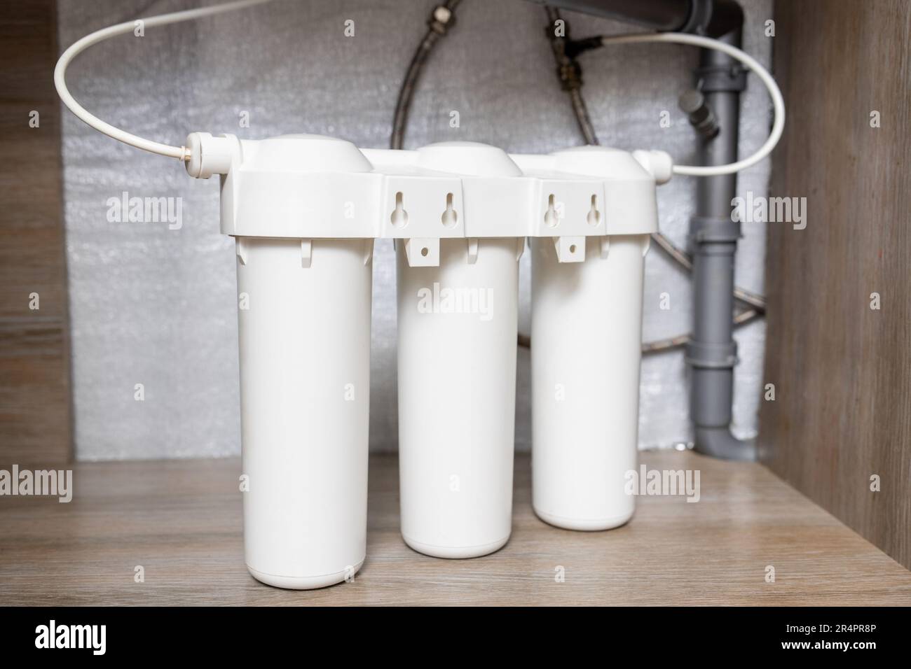 Installazione di filtri di purificazione dell'acqua sotto il lavello della cucina nell'armadio Foto Stock