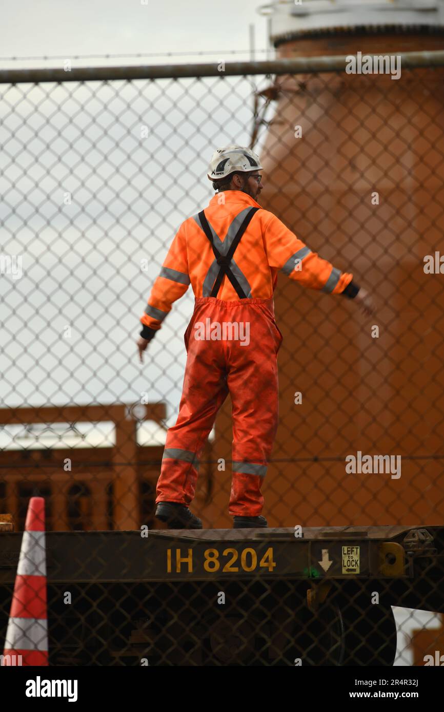 WELLINGTON, NUOVA ZELANDA, 19 MAGGIO 2023: Una banchina sconosciuta dirige una gru che scarica binari ferroviari dalla nave generale danese Maasgracht al porto di Wellington Foto Stock