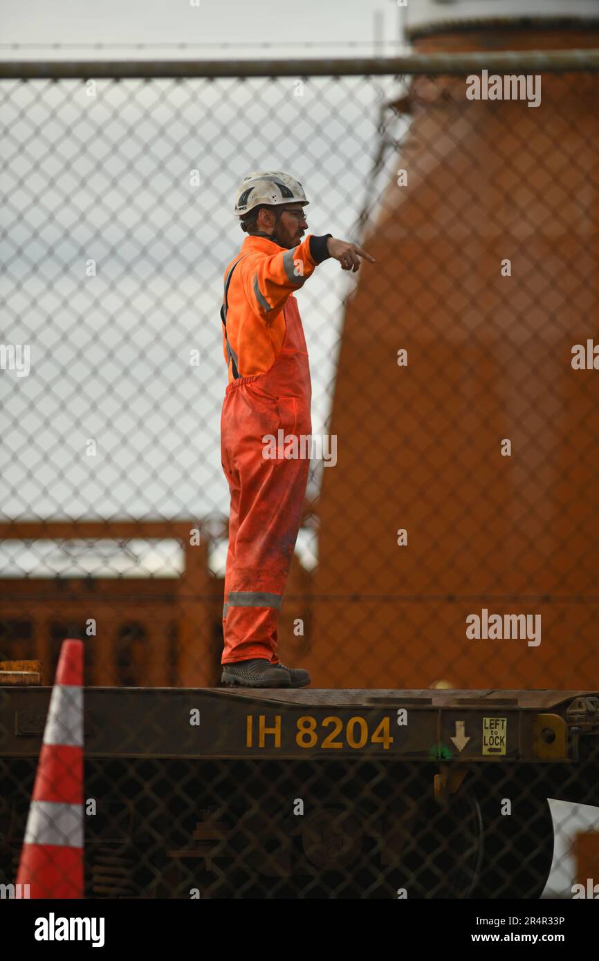 WELLINGTON, NUOVA ZELANDA, 19 MAGGIO 2023: Una banchina sconosciuta dirige una gru che scarica binari ferroviari dalla nave generale danese Maasgracht al porto di Wellington Foto Stock