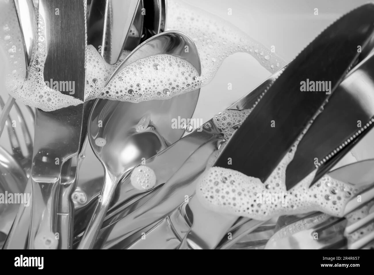 Lavare cucchiai d'argento, forchette e coltelli in lavello con acqua, primo piano Foto Stock