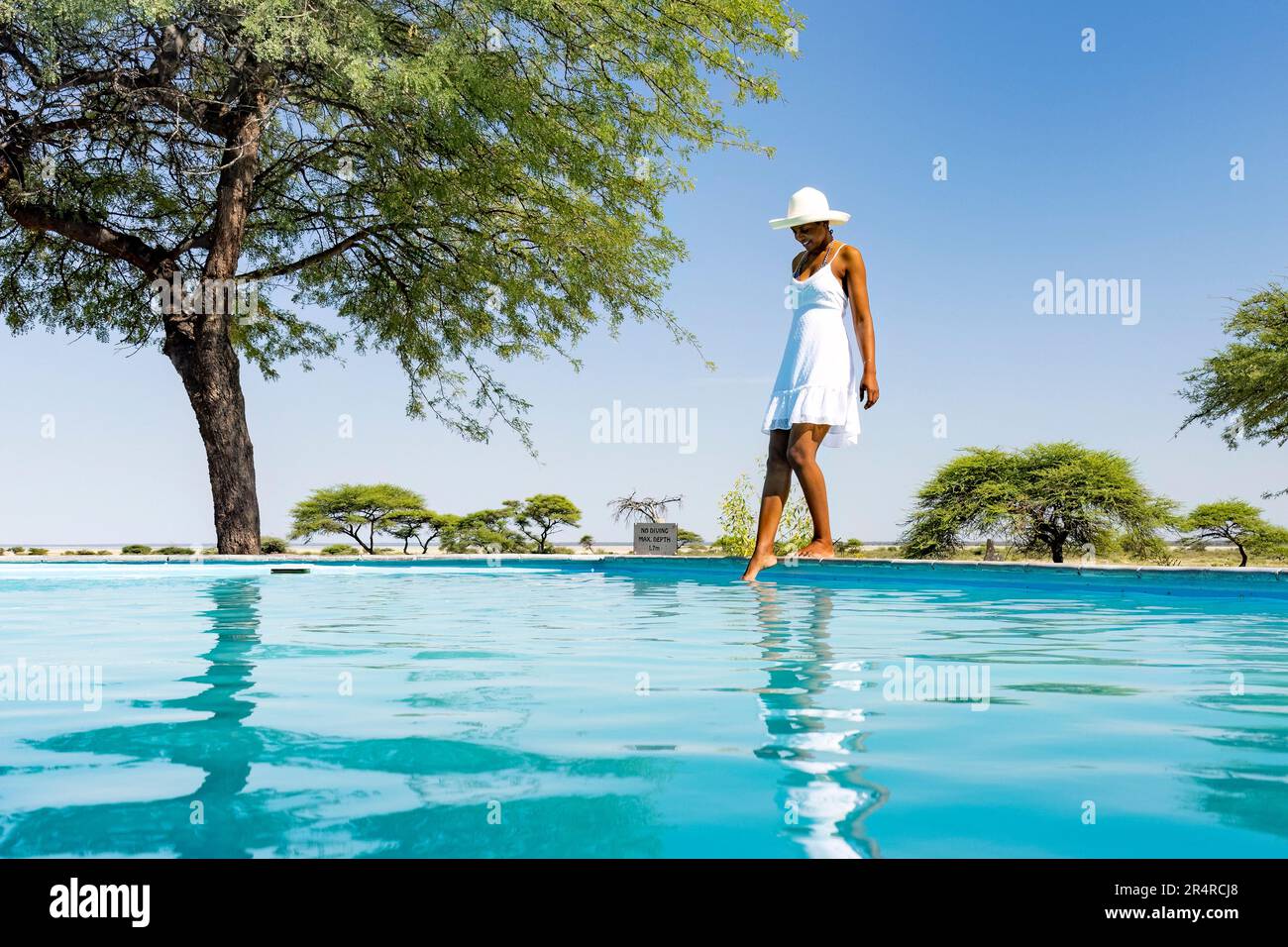 Donna in bianco sundress in piedi accanto alla piscina a Onguma The Fort, Onguma Game Reserve, Namibia, Africa Foto Stock