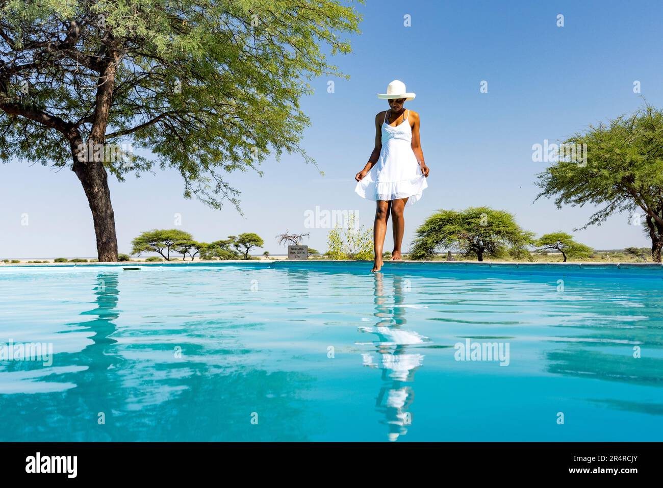Donna in bianco sundress in piedi accanto alla piscina a Onguma The Fort, Onguma Game Reserve, Namibia, Africa Foto Stock