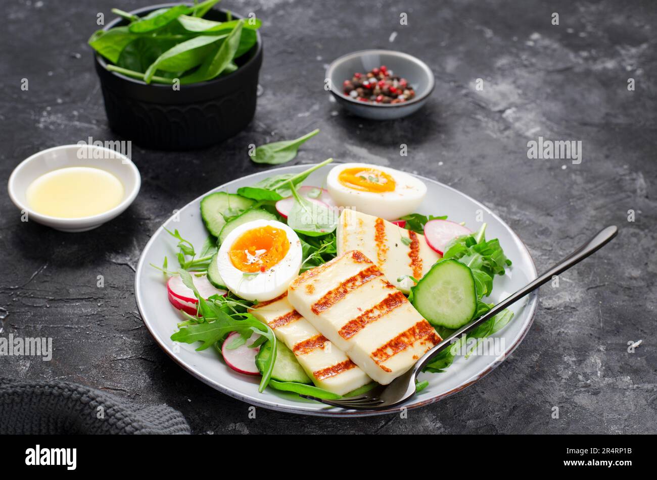 Pasto salutare al paleo Ketogenic, Halloumi alla griglia con lattuga, ravanello, cetriolo, uovo bollito su fondo scuro, Detox, pranzo dietetico Foto Stock