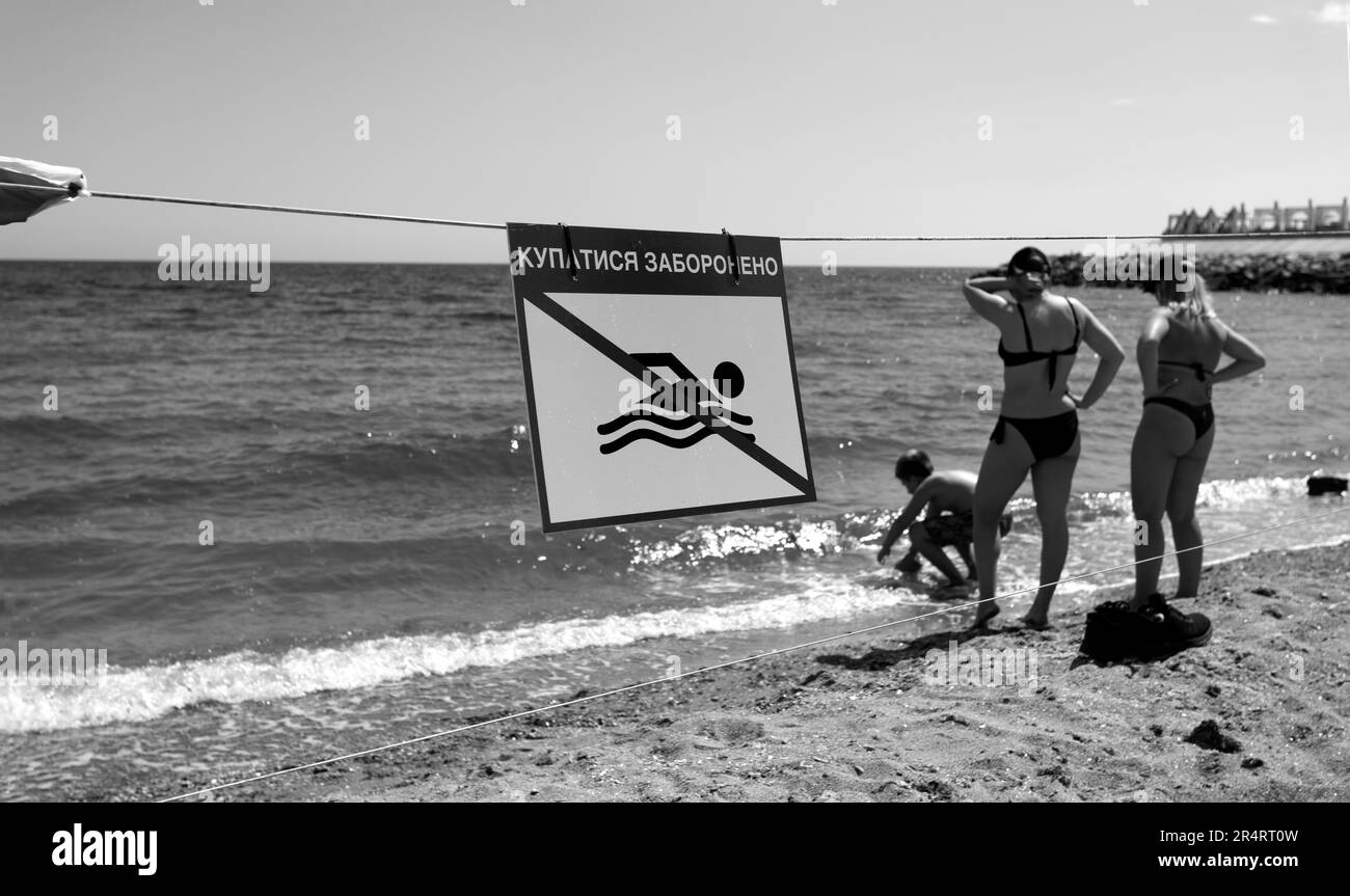 Cartello rosso brillante "No Swimming" sulla spiaggia di sabbia marina della città di Odessa durante l'attacco della Russia all'Ucraina. È vietato nuotare! Avvicinarsi all'acqua è Foto Stock