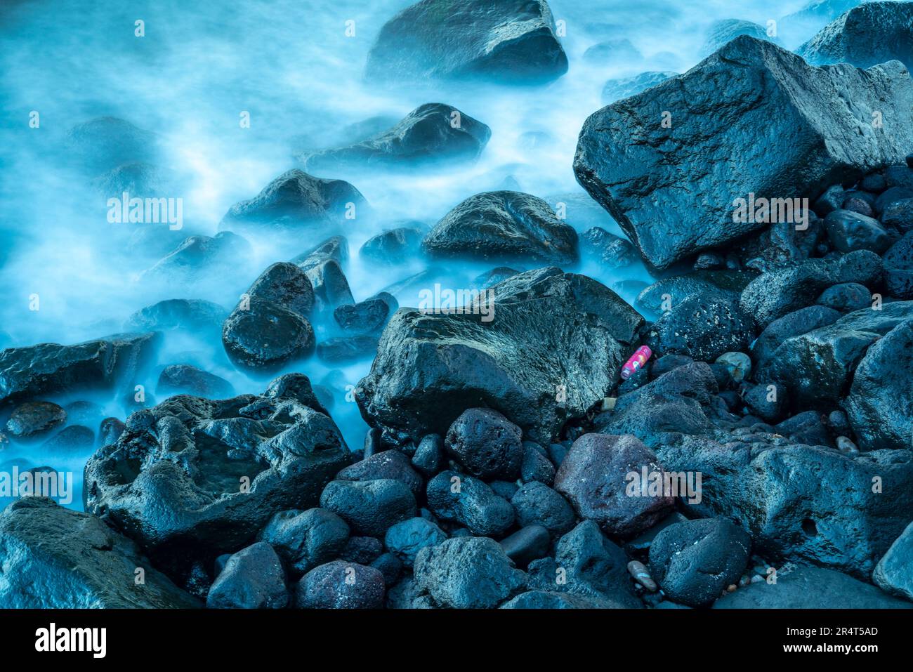 Vista di bottiglie di plastica disparate e le onde sulle pietre sulla spiaggia di Giardini Naxos, Sicilia, Mediterraneo, Italia, Europa Foto Stock