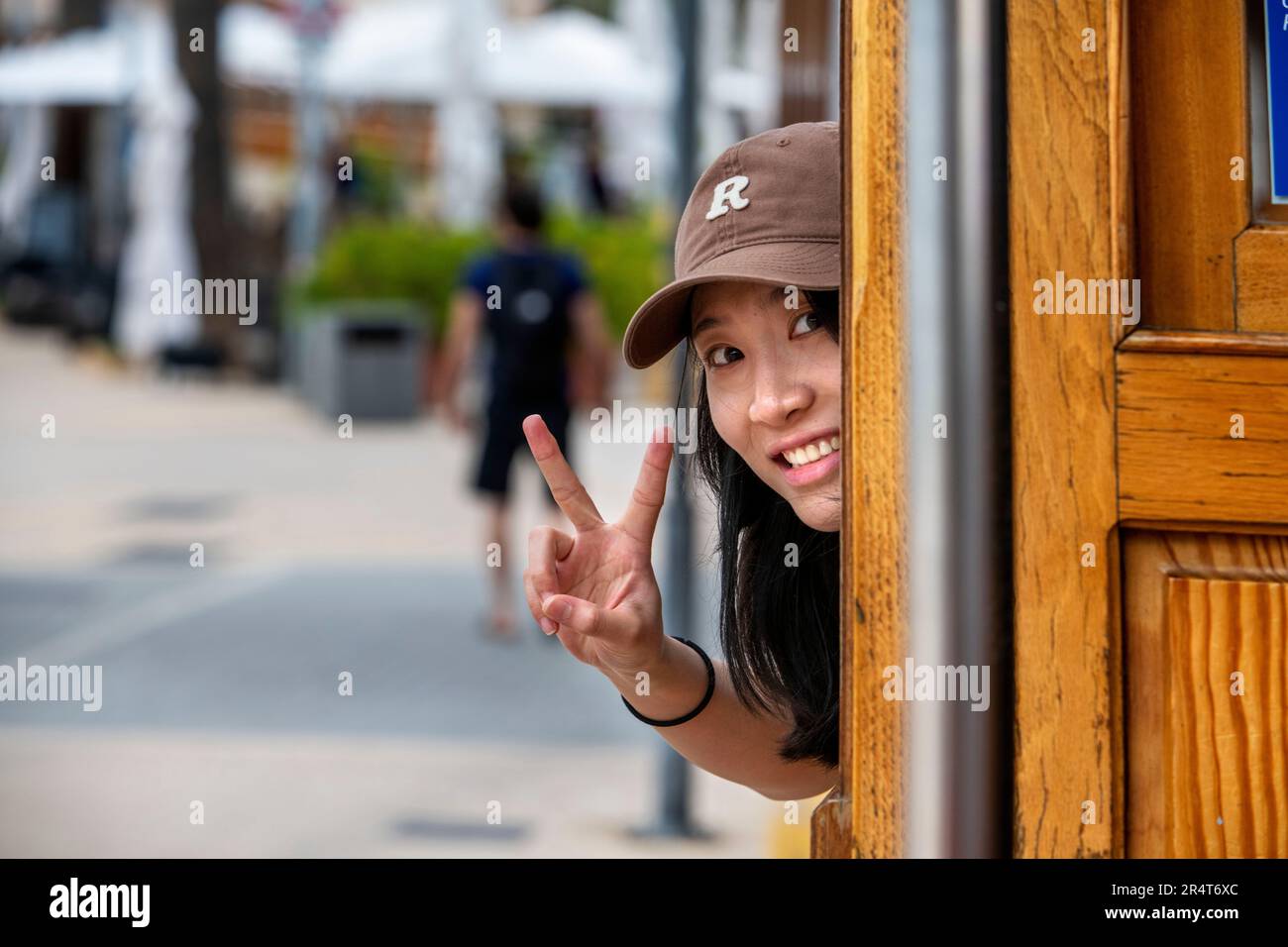 Turista asiatico all'interno del tram d'epoca al porto di Soller centro villaggio. Il tram opera un servizio 5kms dalla stazione ferroviaria di Soller vi Foto Stock