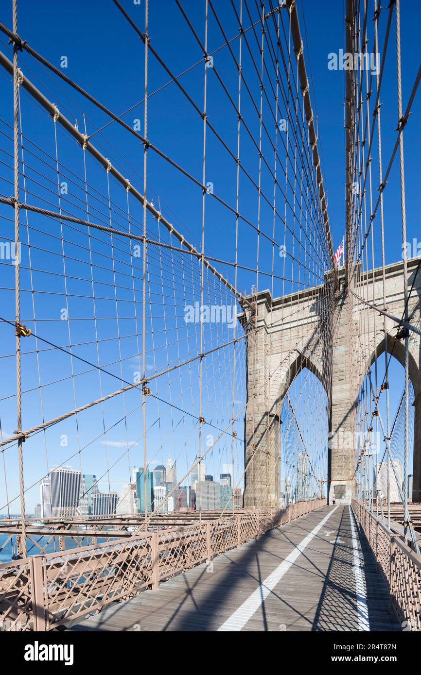 US, New York, passerella del ponte di Brooklyn con piloni e cavi e bandiera degli Stati Uniti. Foto Stock