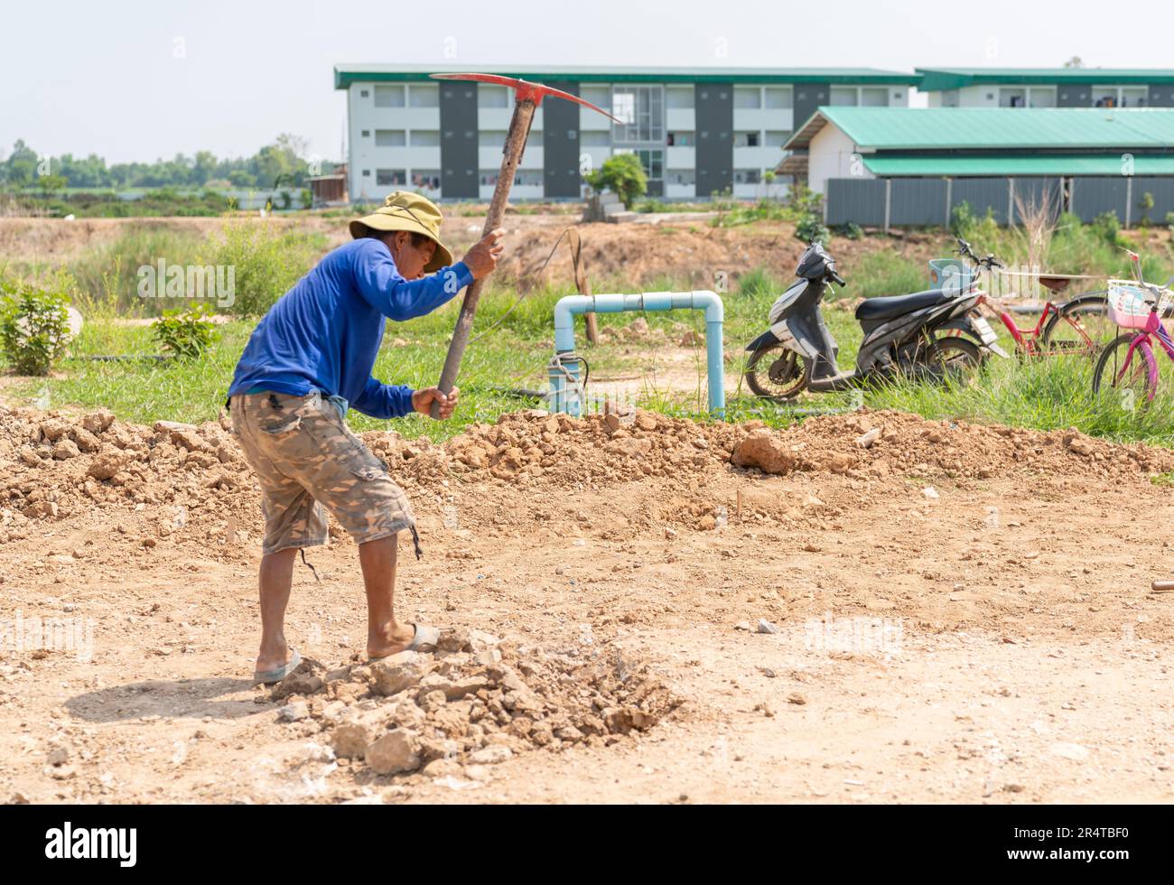 I lavoratori utilizzano pickaxe scavando la superficie del suolo per livellarla prima di versare calcestruzzo. Foto Stock