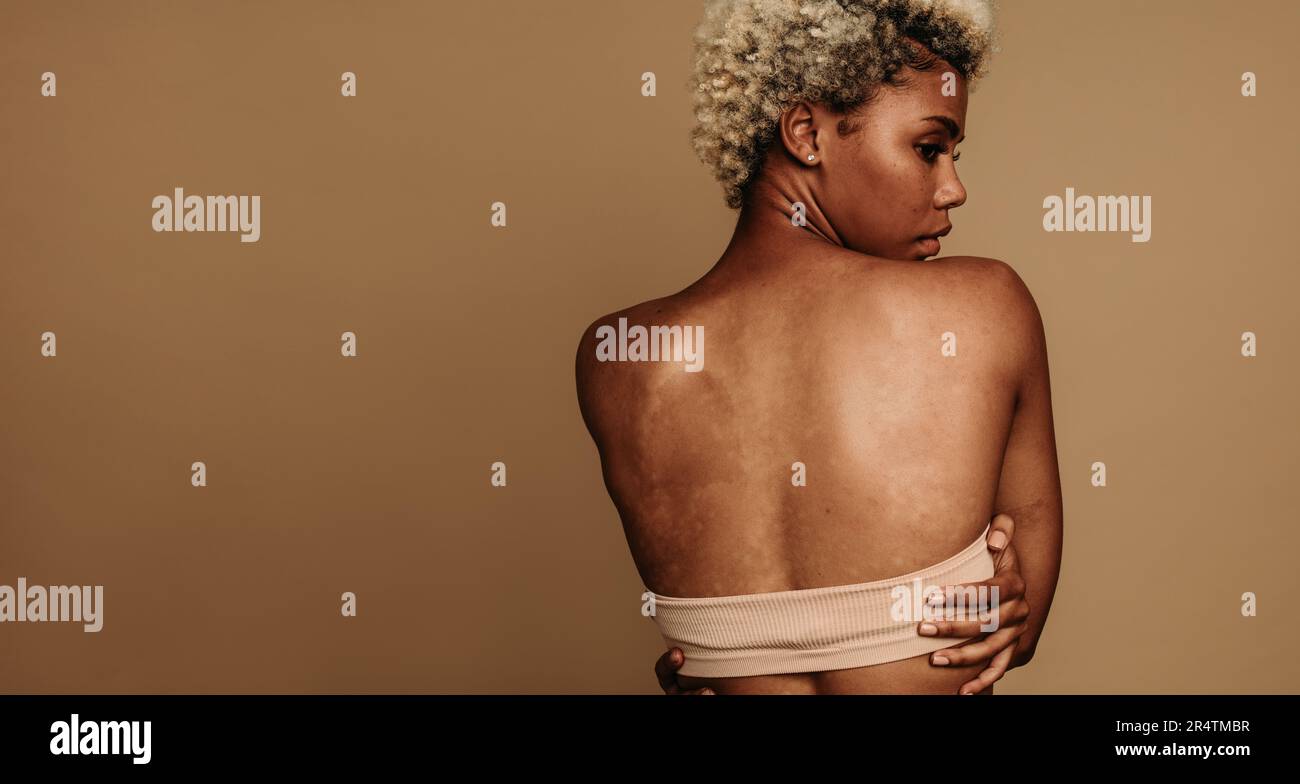 Vista posteriore di una giovane donna in piedi con sicurezza in uno scatto da studio con la schiena alla telecamera. Donna che esprime positività corporea e fiducia in se stessi thro Foto Stock