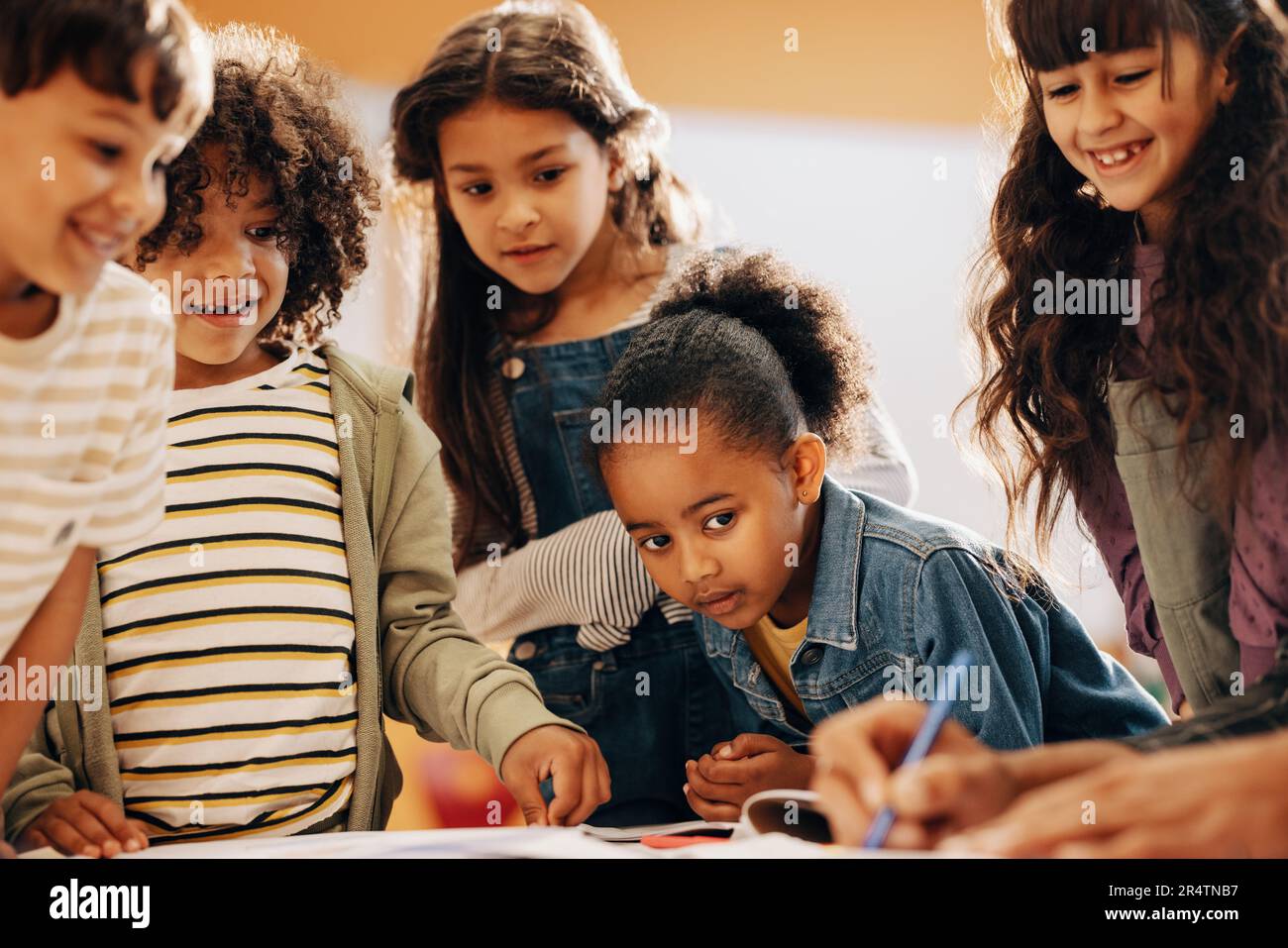 Ragazzi che imparano dal loro insegnante a scuola. Il gruppo di bambini presta attenzione mentre il loro insegnante mostra loro come disegnare in classe. Bambini che scolano in un Foto Stock