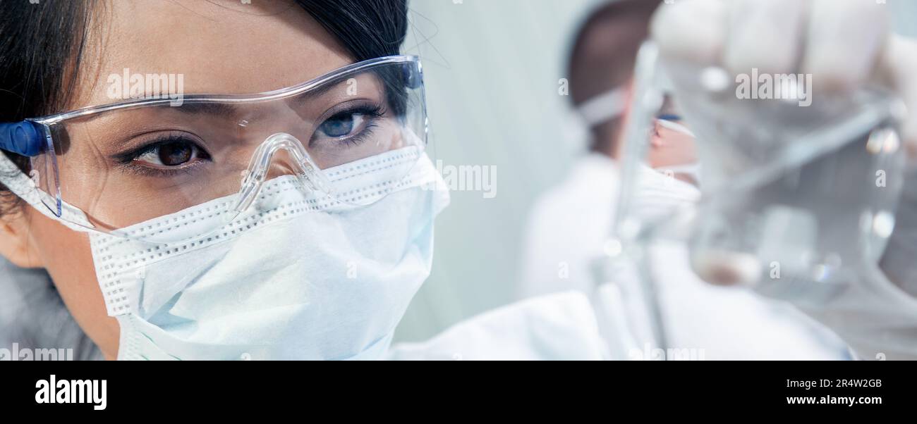 Donna asiatica cinese scienziato medico femminile, ricercatore scientifico o medico che lavora in un laboratorio o laboratorio di ricerca medica con il suo collega behin Foto Stock