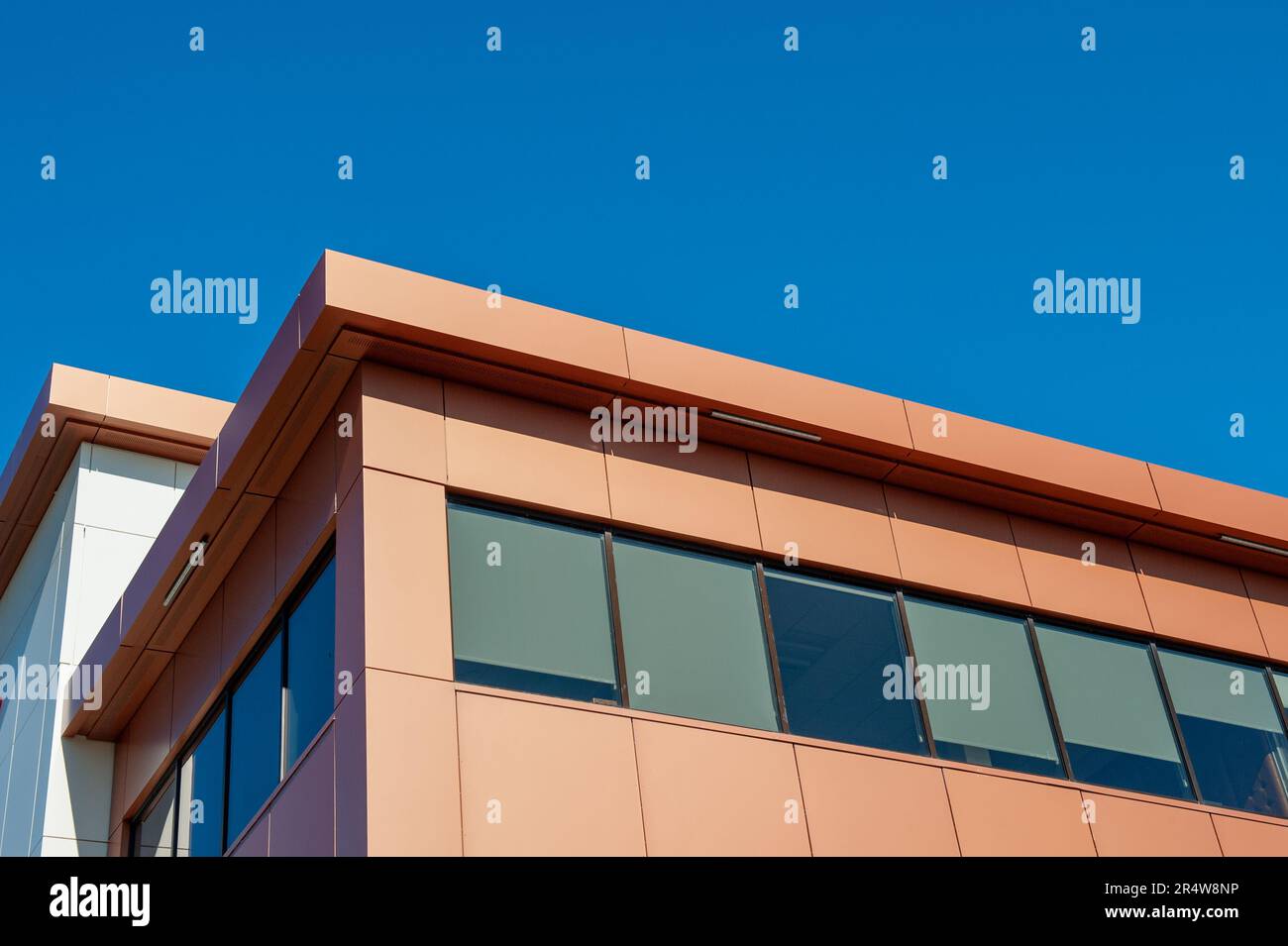 I tetti di un moderno edificio commerciale sotto il cielo blu e le nuvole bianche. L'esterno del nuovo edificio e' arrugginito, arancione e crema in metallo di colore Foto Stock