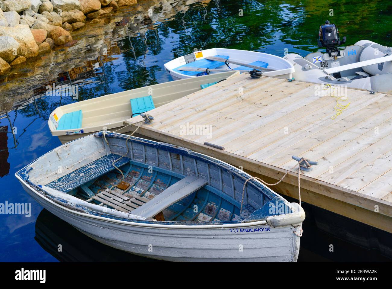 Piccole barche dixie dingy in fibra di vetro bianca ormeggiate ad un pontile galleggiante in legno. Lo skiff viene utilizzato per il trasporto come tender tra navi in un molo. Foto Stock