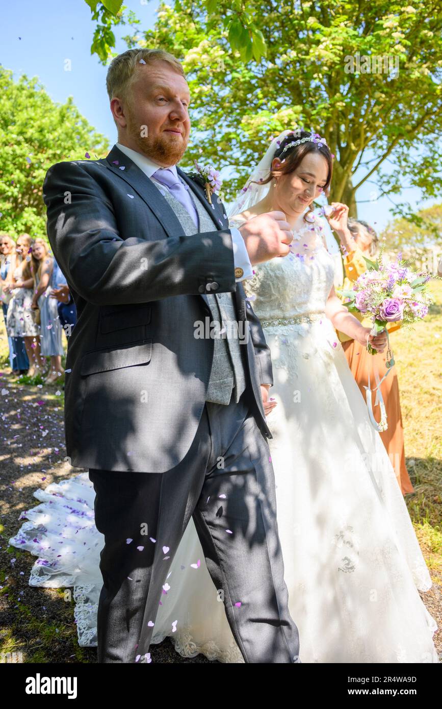 Sposa e sposo che camminano tra coriandoli dopo il matrimonio Foto Stock