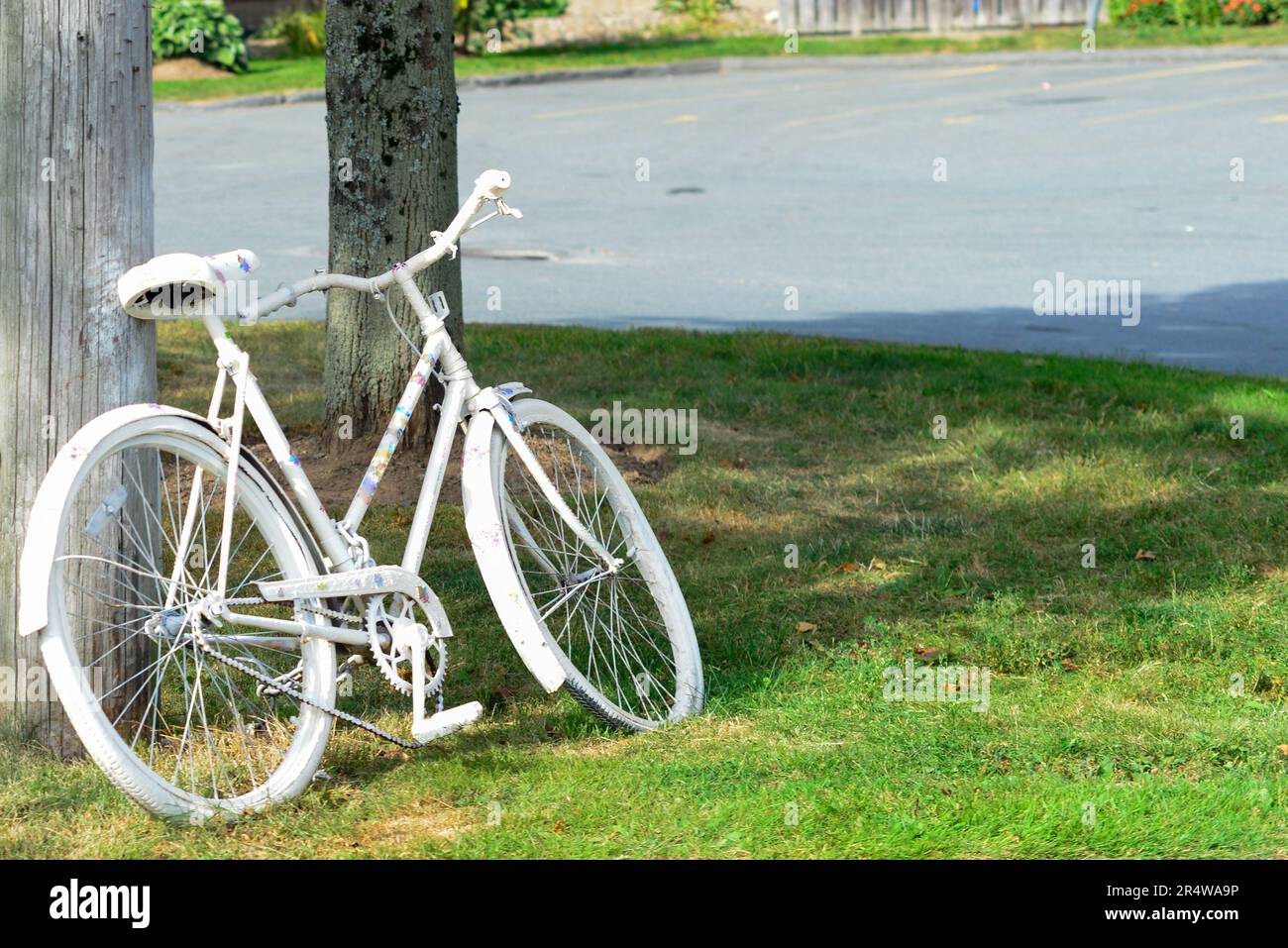Una bicicletta per adulti dipinta di bianco come luogo commemorativo di un precedente incidente ciclistico. La bicicletta fantasma è un simbolo di memoria e un promemoria per condividere la strada. Foto Stock