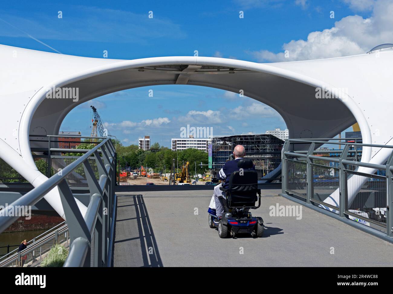 Uomo su scooter per la mobilità su un nuovo ponte pedonale eretto sulla strada A63, per collegare il porto turistico e il centro città, Hull, East Yorkshire, Humberside, Inghilterra UK Foto Stock