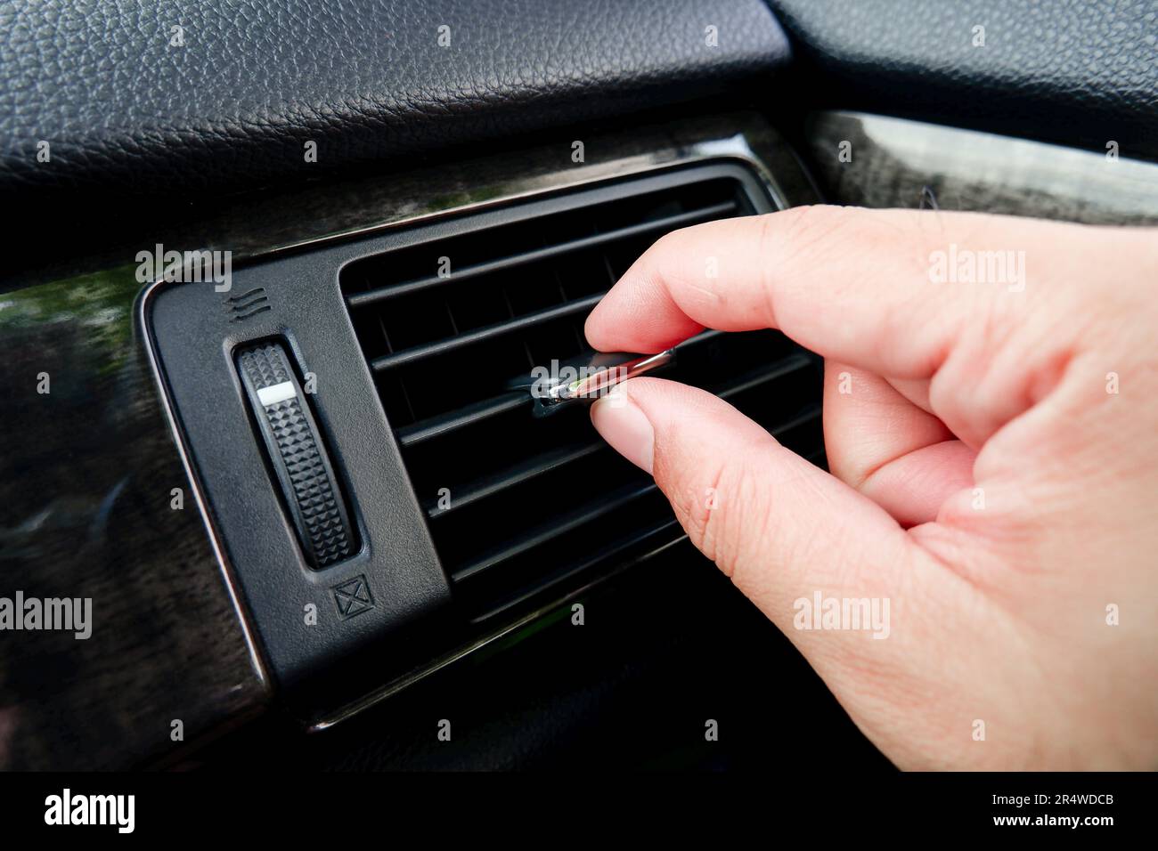 La mano dell'uomo regola la direzione del vento del condizionatore dell'auto nell'abitacolo. Foto Stock