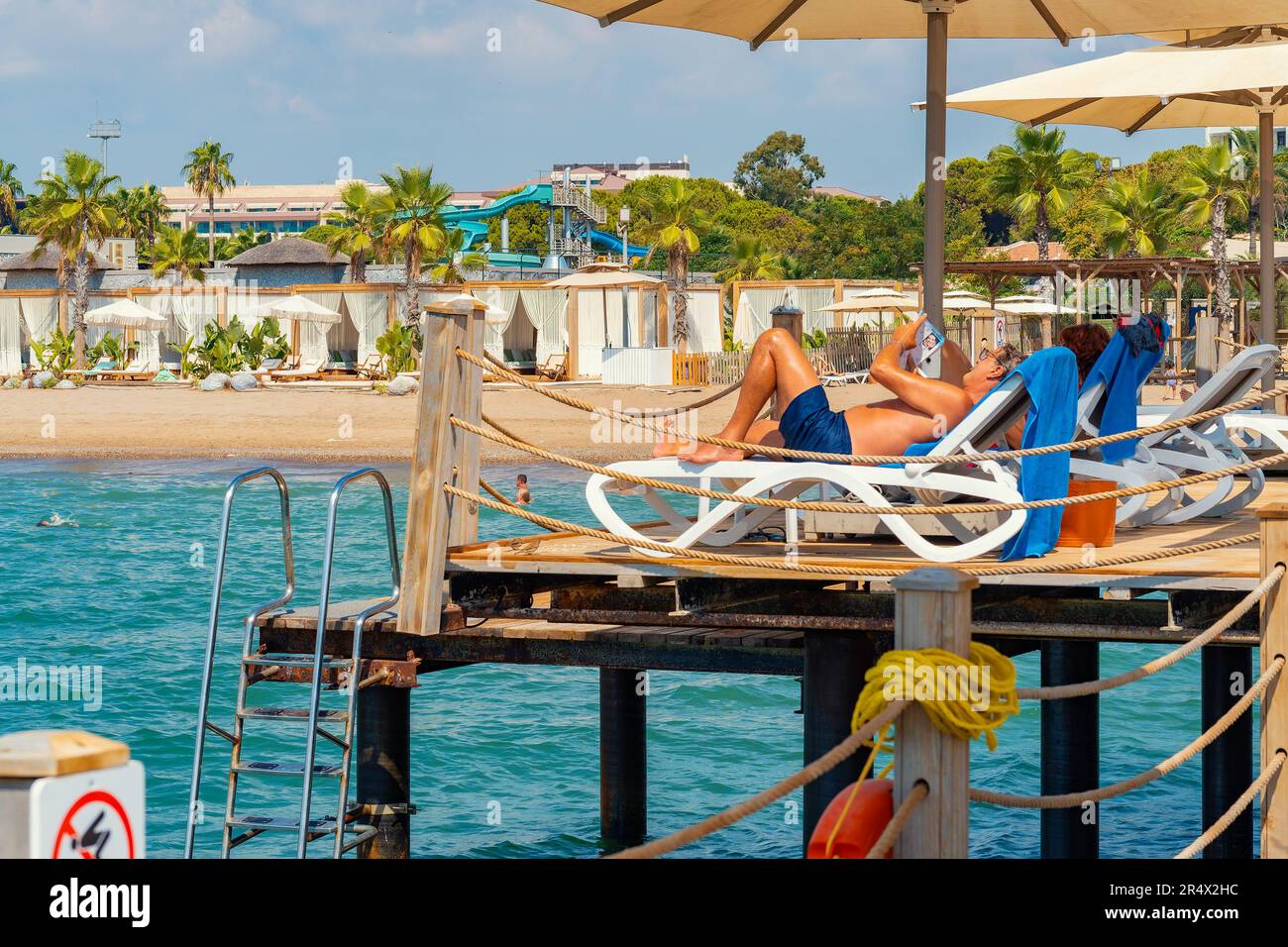 Antalya; Turchia-settembre 11; 2022: Persone che prendono il sole sui lettini sotto gli ombrelloni sul molo di legno in estate. Antalya una città popolare per il russo, Ucraina Foto Stock