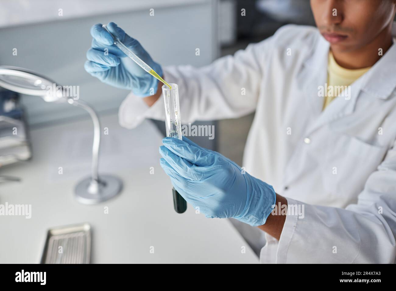 Primo piano di un giovane uomo che tiene la provetta mentre fa la ricerca in laboratorio, copia spazio Foto Stock